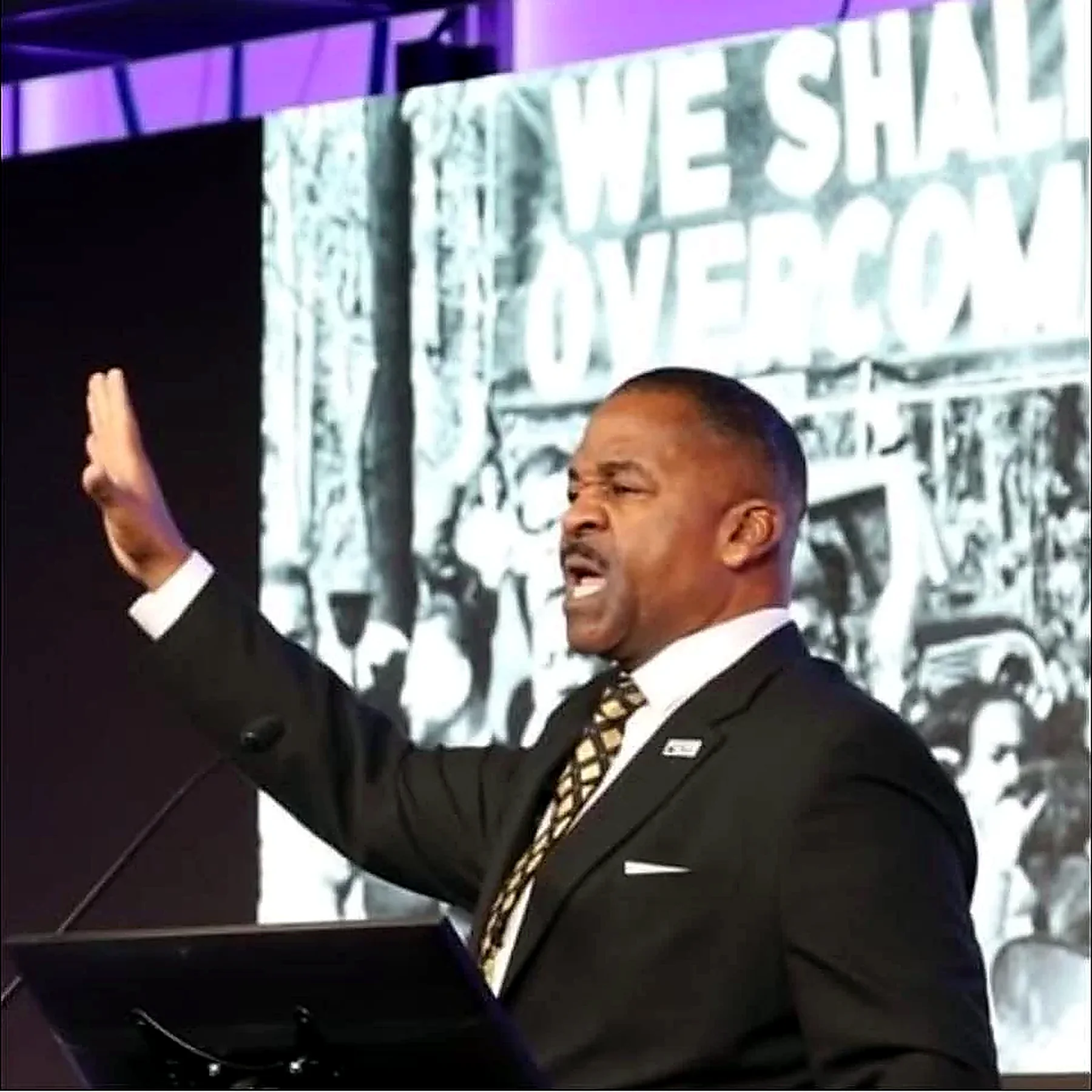 Rev. Dr. John Moore performing before a We Shall Overcome backdrop